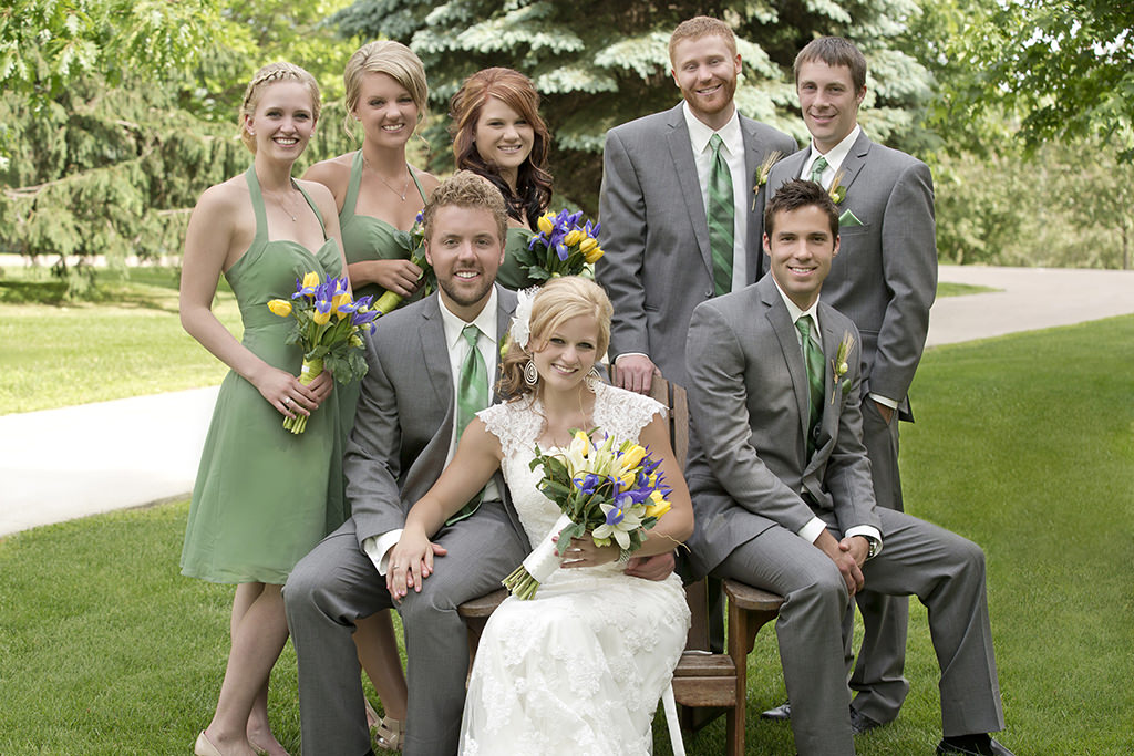 Wedding photography showing the bride, groom, and the whole wedding party smiling and posing for a photo.