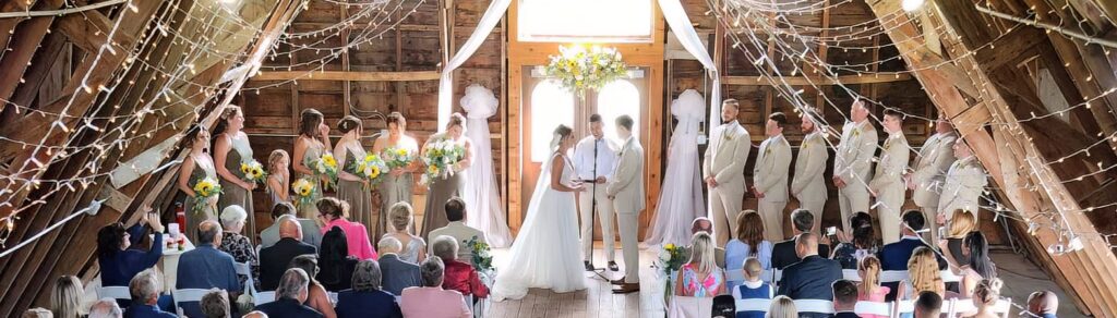 Couple at their wedding ceremony inside a beautiful barn surrounded by friends and family.